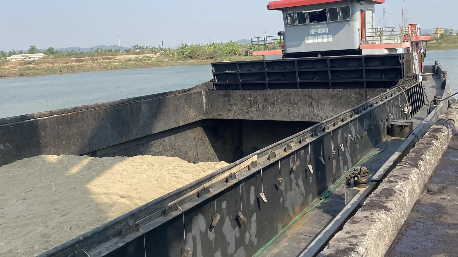 Sà lan chở đầy cát san lấp di chuyển trên sông